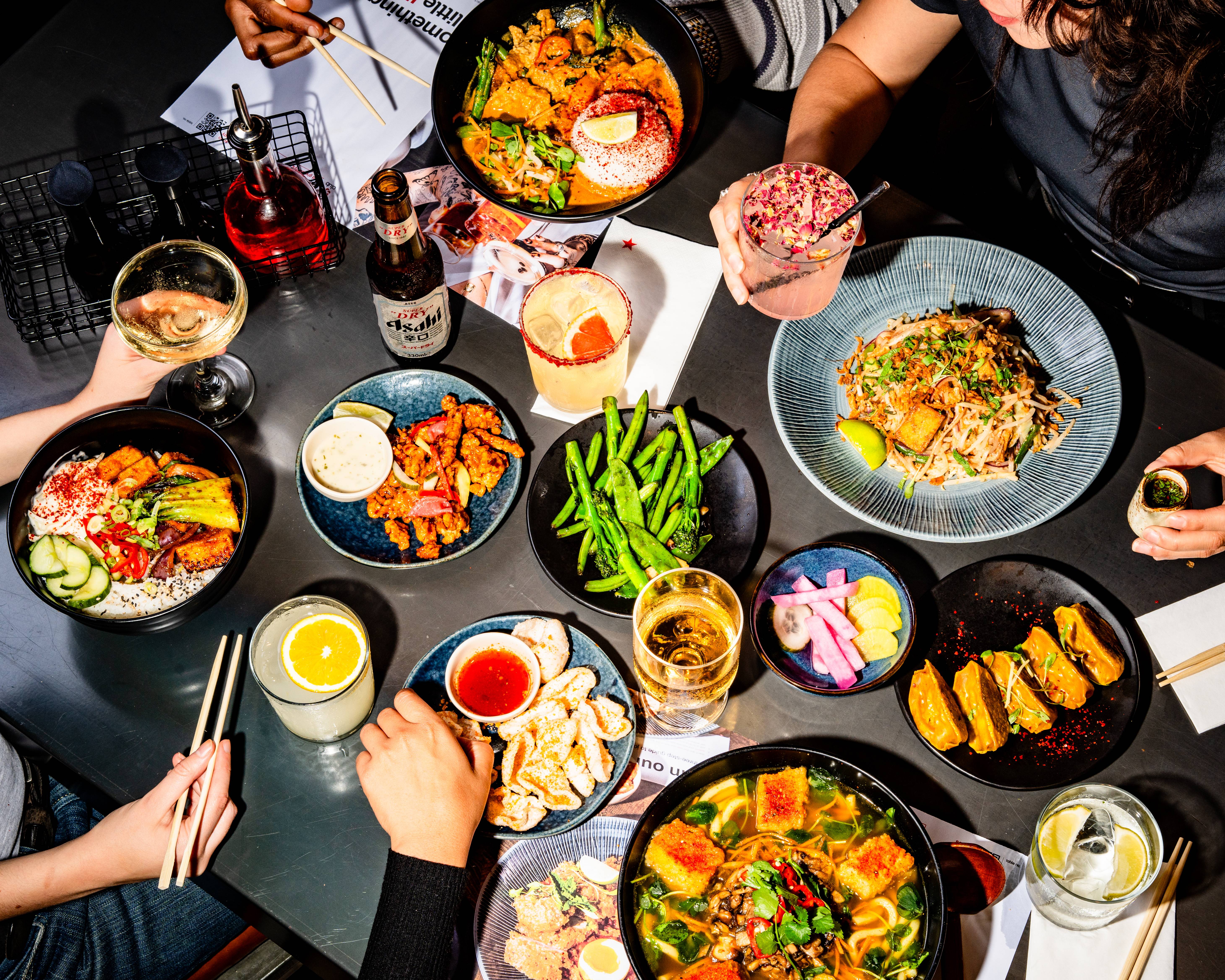 a table full of delicious wagamama food and drink being enjoyed by a group of friends