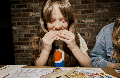 a little girl taks a big bite of a bao bun